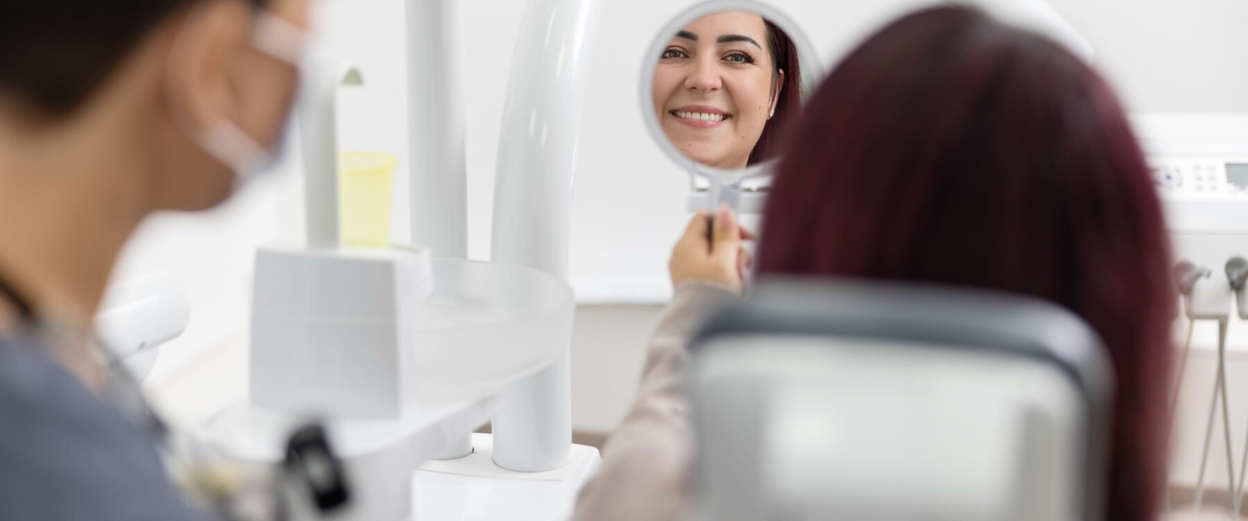 Patientin begutachtet Endergebnis lächelnd im Spiegel